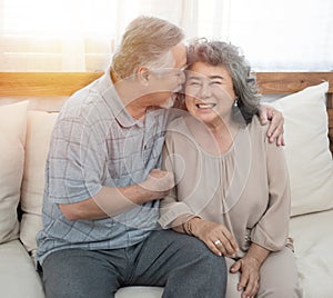 Elderly senior asian couple happy together at home.Grandfather and grandmother sit on coach in living room at home have leisure