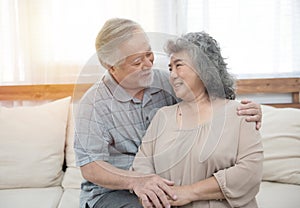 Elderly senior asian couple happy together at home.Grandfather and grandmother sit on couch in living room at home have leisure