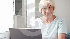 Elderly senior blond woman working on laptop computer at home. Received good news excited and happy