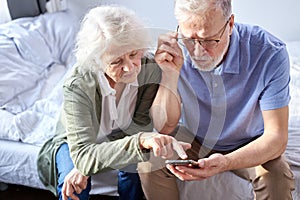 elderly senior couple looking at children's photos in smartphone