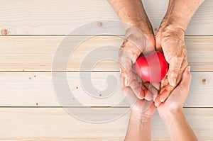 Elderly senior or grandparent's hands with heart in support of nursing family caregiver for national hospice palliative care