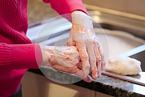 Elderly senior lady applying hand cream to old wrinkled cracked dry hands to moisturise for skin care photo