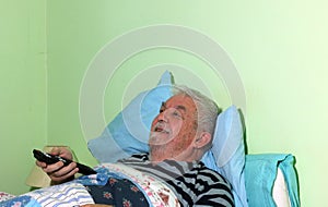 Elderly or senior man in bed with remote control.