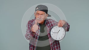 Elderly senior man showing time on clock watch, ok, thumb up, approve, pointing finger at camera