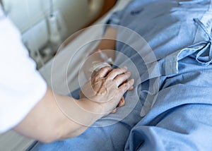 Elderly senior patient ageing old adult person lying in hospital bed with family caregiver or caretaker nurse in nursing photo