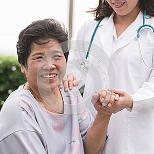 Elderly senior patient Asian old aging person in nursing hospice home holding geriatrician doctor`s hand having happy health