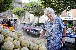 Elderly senior woman buying fresh vegetables and fruits in farmer`s market during summer day in provence france