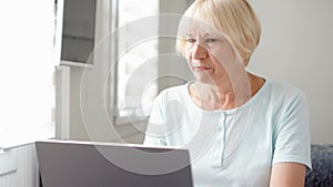 Elderly senior woman receiving very bad news on his laptop computer screen and upset