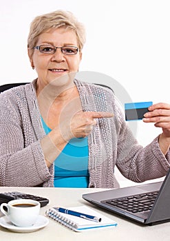Elderly senior woman showing credit card, paying over internet for utility bills or shopping