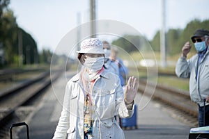 Elderly seniors people with face masks waiting train before traveling during a coronavirus pandemic