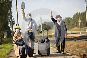 elderly seniors people with face masks waiting train before traveling during a pandemic
