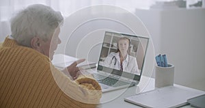 Elderly sick man is calling by video chat to doctor, young female physician is answering to him and consulting