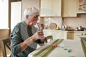 Elderly sick man with glass of water taking pill