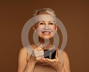 Elderly smiling fashionable positive happy blonde caucasian woman hold a mug of coffee