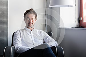 Elderly smiling man relaxing in a sofa near of a window