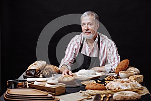 Elderly smiling professional chef man. Isolated over black background