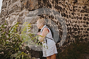 Elderly smiling senior traveling backpacker mature woman tourist walking posing outdoors in ancient Europe fortress
