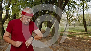 Elderly sport man stops after running, using smart watch, checking heart rate during fitness