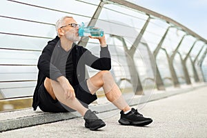 Elderly sportsman drinking water, have break during outdoor workout