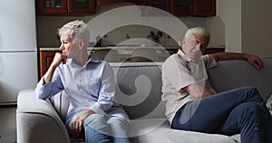 Elderly spouses on brink of divorce sits on sofa apart