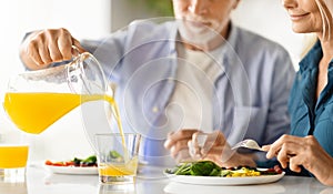 Elderly spouses having breakfast together in kitchen, cropped shot