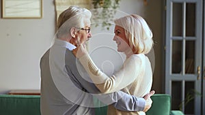 Elderly spouses talking dancing waltz in living room