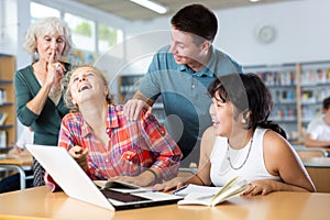 Elderly teacher asks to be quieter than noisy teenagers in school library