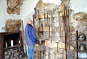 An elderly tourist considers old knives in the museum. Shaaken Castle, XIII century. Kaliningrad region