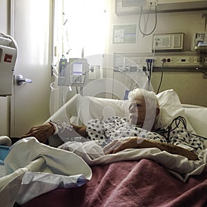Elderly, white haired male patient in hospital bed