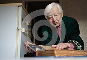 Elderly widowed woman holds photos of her deceased husband and gets emotional on valentine`s day remembering old times.