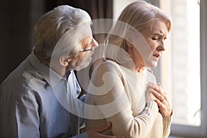 Elderly wife holding hand on chest worried husband supporting her