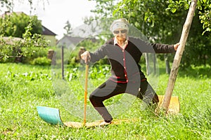 An elderly woman of 90 years old, with gray hair and a headband, doing fitness in the garden