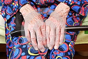 Elderly woman of 90 years put her hands on a cane, retirement and disability, close up.Elderly people are susceptible to the virus