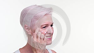 Elderly Woman Applying Face Cream on White Background