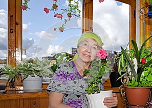 An elderly woman on the balcony with potted flower