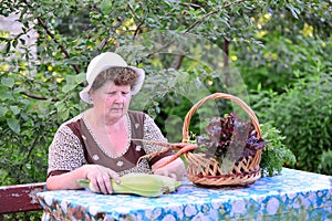 Elderly woman with basket of vegetables sitting at the table