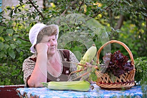 Elderly woman with basket of vegetables sitting at the table