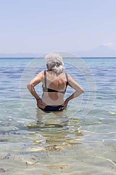 elderly woman in bathing costume entering the sea