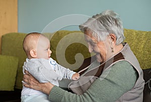 Elderly woman with a beautiful baby at home.