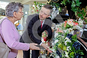 Elderly woman buying flowers at funeral service