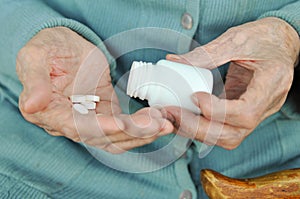 An elderly woman with a cane holding a pill and a container on the street. Health.Mockup. Close up.