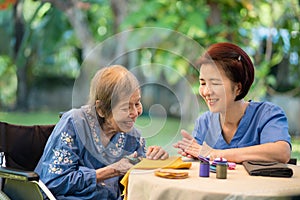 Elderly woman with caregiver in the needle crafts occupational therapy  for Alzheimer or dementia