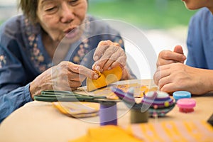 Elderly woman with caregiver in the needle crafts occupational therapy  for Alzheimer or dementia