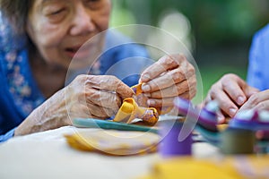 Elderly woman with caregiver in the needle crafts occupational therapy for Alzheimer or dementia