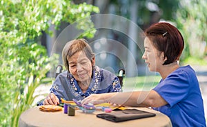 Elderly woman with caregiver in the needle crafts occupational therapy  for Alzheimer or dementia
