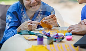 Elderly woman with caregiver in the needle crafts occupational therapy  for AlzheimerÃ¢â¬â¢s or dementia