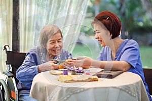 Elderly woman with caregiver in the needle crafts occupational therapy  for Alzheimerâ€™s or dementia