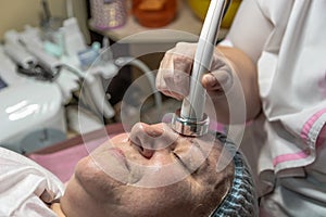 An elderly woman carries out a cosmetic procedure for the face.