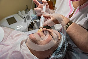 An elderly woman carries out a cosmetic procedure for the face.