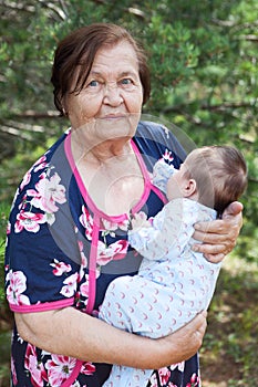 Elderly woman carrying a baby in arms, great grandmother portrait with her great grandchild
